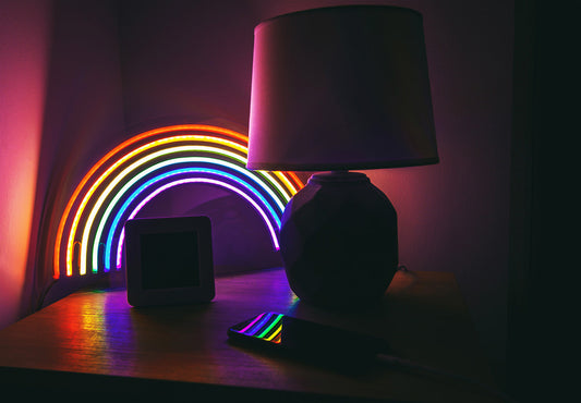 RGB rainbow neon light glowing next to a bedside lamp in a dark, stress-free bedroom